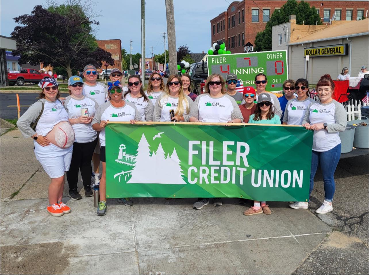 Image of a group of people holding a Filer Credit Union Banner at a festival